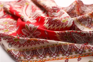 Macro detail of red paisley printed silk scarf showing smooth texture and ethnic patterns