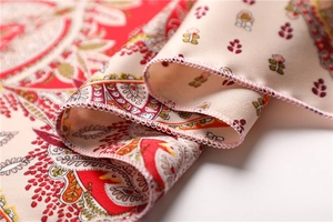 Macro shot of paisley print silk scarf showing red satin fabric and fine edge stitching