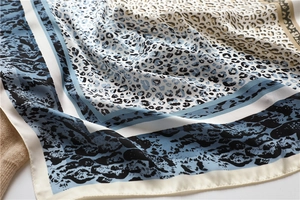 Detailed close-up of leopard print silk scarf with blue and beige color blocking texture