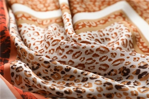 Close-up of leopard print silk scarf showing soft texture and orange contrast border