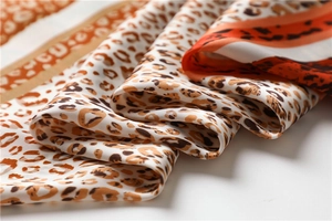 Detail shot of silk scarf fabric showing leopard print and orange stripes texture