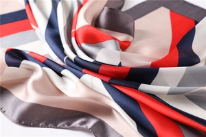 Close-up of geometric color block silk scarf featuring leopard print and rolled hem detail