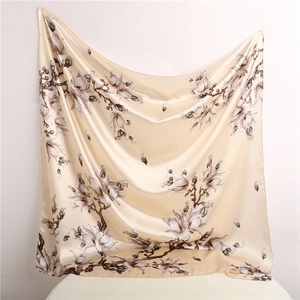 Detailed texture of the champagne silk scarf featuring elegant white magnolia floral patterns
