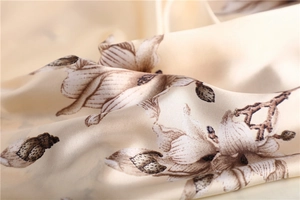 Macro detail of silky satin champagne scarf featuring elegant brown floral patterns