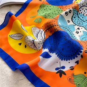 Vibrant colorful patterned silk square scarf on white faux fur background