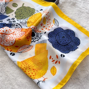 Detail of colorful silk-like scarf with artistic bird and heart prints on white plush rug