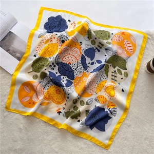 Detail of bohemian floral square silk scarf with vibrant yellow border on plush white rug