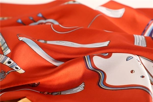 Detailed view of red satin silk scarf showing intricate tassel patterns and smooth texture