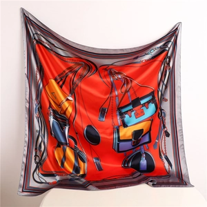 Detail of red square silk scarf with leather bag and chain patterns on satin fabric