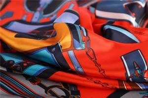 Macro shot of red satin silk scarf showing intricate chain prints and luxury texture