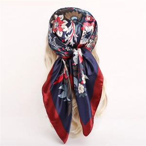 Floral satin silk scarf in navy blue with red flowers worn as a stylish headscarf