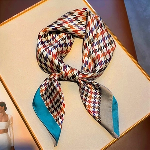 Elegant houndstooth silk scarf in orange and blue displayed on a gold-framed board