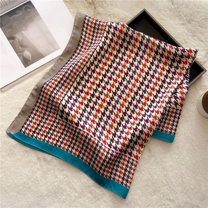 Detail of silk scarf with houndstooth pattern and bright blue border on soft fur rug
