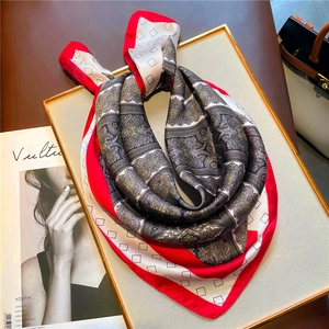 Detailed shot of a luxury paisley silk scarf with red border on a golden display tray