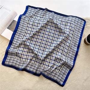 Detail view of blue houndstooth silk scarf on soft beige textured background