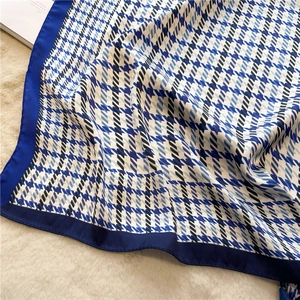Detailed view of luxury houndstooth silk scarf on soft white textured backdrop