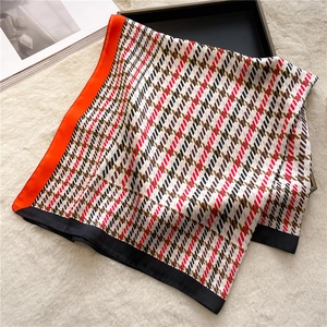 Close-up of houndstooth silk scarf with orange borders on soft white faux fur texture