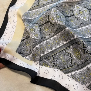 Detailed macro view of vintage paisley and geometric block patterns on a silky square scarf