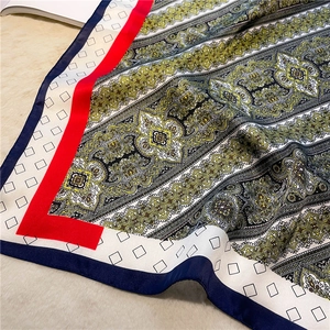 Detailed close-up of premium satin scarf with paisley prints and color-block borders