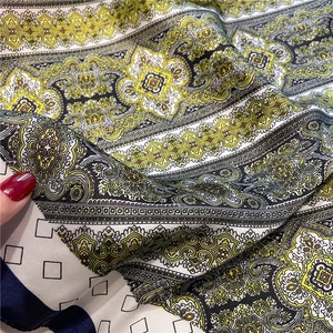 Detailed close-up of vintage paisley print on smooth satin fabric with dark navy edges