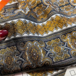 Macro shot of paisley pattern on silky fabric with baroque gold and black print