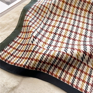 Detailed view of the geometric houndstooth pattern and silk texture of the square scarf