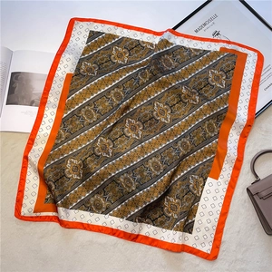 Detailed shot of vintage paisley silk scarf with orange borders on a plush background