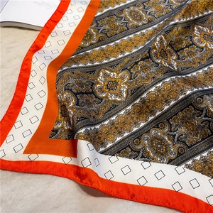 Macro shot of vintage baroque pattern silk scarf with elegant orange border and gold texture