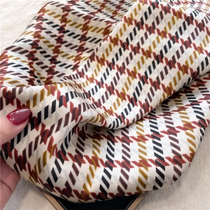Detail of soft silk scarf with houndstooth pattern and elegant caramel geometric print