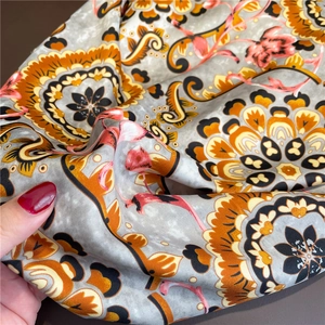 Detailed close-up of mandala and paisley printed silk scarf showing smooth satin texture