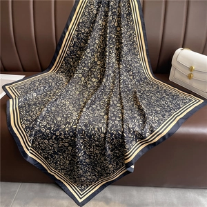 Détail d'un grand foulard en satin noir orné d'un élégant motif floral doré