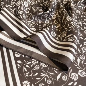 Détail d'un foulard en soie haut de gamme avec motifs floraux et bordures rayées chic