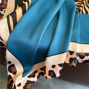Close-up of leopard and zebra print silk scarf with peacock blue satin texture