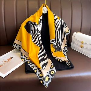 Vibrant yellow silk square scarf with zebra and leopard print on a dark leather background