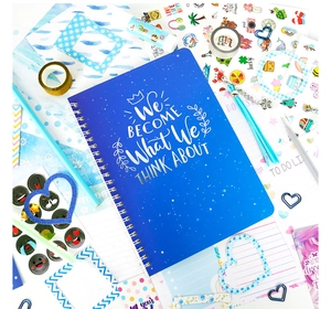 Detailed top view of blue spiral journal notebook with motivational quotes and stickers