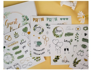 Detailed view of wedding guest book with gold heart stickers and botanical decorations