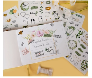 Detailed view of wedding guest book and themed decorative stickers for scrapbooking