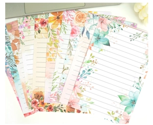 Flat lay of watercolor floral stationery set with lined paper and artistic botanical patterns