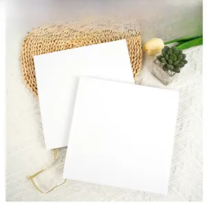 Square white guestbook with gold ribbon bookmark on aesthetic fabric background