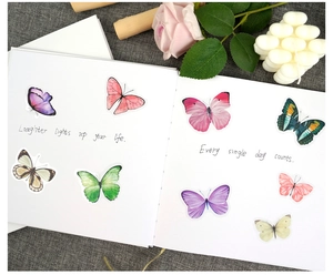 Detailed view of colorful watercolor butterfly stickers inside a blank wedding guestbook