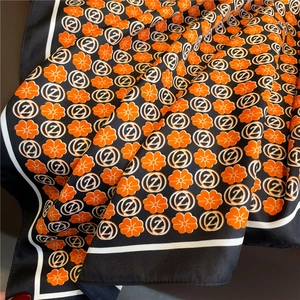 Detail of floral silk scarf with black borders and orange flower pattern texture
