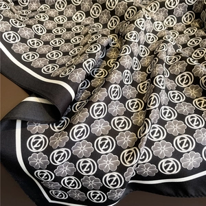 Detail of silk scarf showing black and white floral prints with elegant draped fabric texture