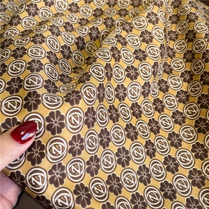 Macro view of floral pattern satin scarf with golden-brown finish and silk-like texture