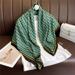 Elegant green clover print silk scarf with black border draped over a white t-shirt