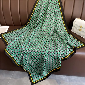 Detail of silk-like square scarf with green clover patterns and contrast borders