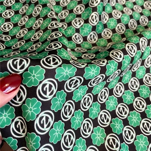 Detail of silk-like twill scarf showing green floral print and Z logo on black fabric