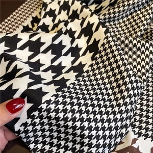 Macro view of silky houndstooth twill fabric showing drape and smooth satin texture
