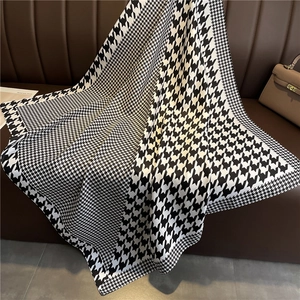 Close-up of elegant black and white houndstooth silk scarf on a brown leather texture