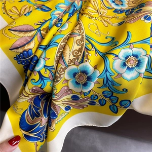 Gros plan d'un foulard en soie avec motifs floraux baroques et tissu jaune doré soyeux