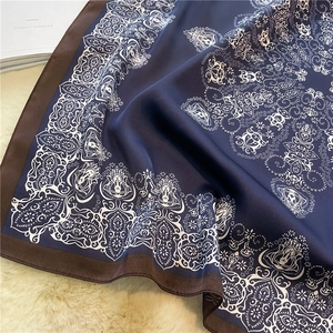 Macro shot of silk-textured paisley scarf with navy blue mandala patterns and brown edges